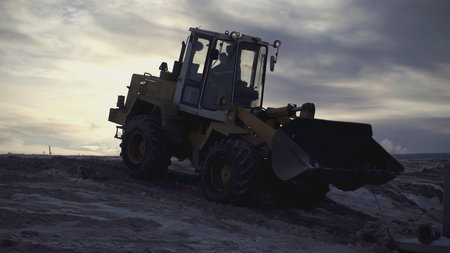 In the foreground, a tractor is pulling a heavy load. In the video, people walk and tractors work on...