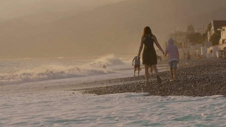 Beautiful embankment by the sea.Creative. People walking next to the raging waves of the sea along the shore with stones and residential buildings are located nearby.の写真素材