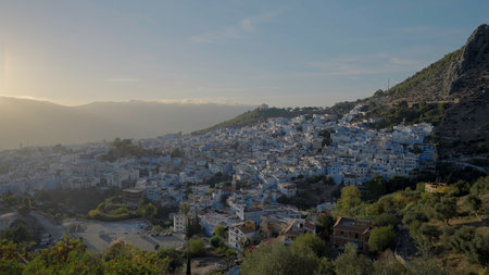 Birds-eye view.Action. A beautiful landscape and a view of the city with small houses which is located on the mountains with green trees against the blue sky.の写真素材