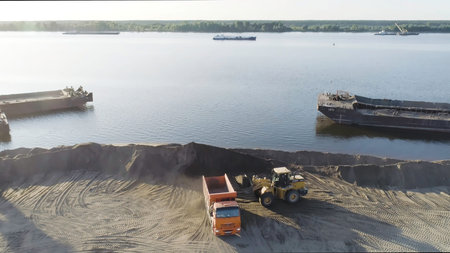 Excavator clearing beach. Scene. Top view of clearing of beach area. Excavator and dump trucks clean...