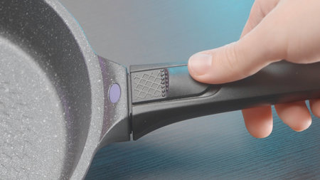 Close up of new frying pan with removable handle. Action. Concept of kitchen utensils for cooking.の写真素材