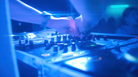 Woman works behind music mixer. Clip. Young woman behind DJ setup in club. Cool female DJ puts on...