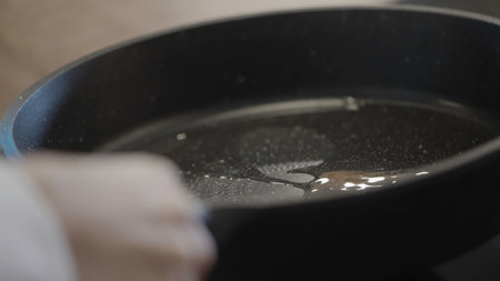 Cooking concept. Action.A large black frying pan on which oil is poured and smeared for fryingの写真素材