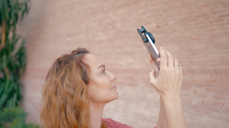 Beautiful young woman shooting a video. Action. A beautiful woman with long hair who shoots videos with amazing accessories on it.の写真素材