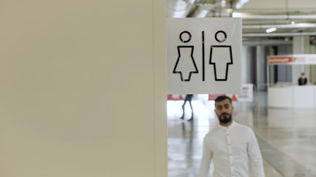 Young man walking inside the public bathroom inside shopping mall. HDR. Man entering toilet room.の写真素材