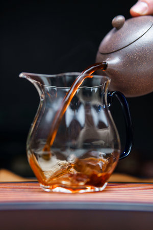 Experience the captivating and elegant tea pouring ritual conducted with a beautiful glass pitcherの写真素材