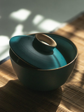 Beautiful teal ceramic bowl with a lid on a bamboo surface, enhancing any settings aesthetics