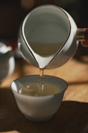 Pouring a comforting cup of tea into a beautiful fine ceramic cup enhances the ritualの写真素材