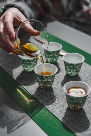 Pouring tea into beautifully crafted traditional cups with elegant designs for enjoymentの写真素材