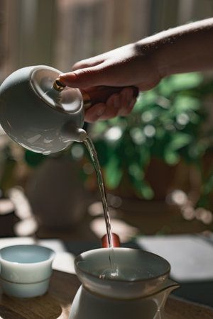 The Art of Elegant Tea Pouring in Soft Natural Light Creating a Serene Atmosphereの写真素材