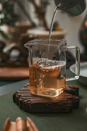 Pouring aromatic tea into a beautiful glass jug, surrounded by various natural elementsの写真素材