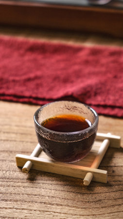 A Delicate Ceramic Cup Filled with Tea is Gracefully Placed on a Beautiful Wooden Table Settingの写真素材