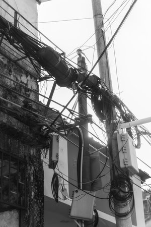 A Dedicated Urban Worker Skillfully Positioned on an Electrical Pole Surrounded by Wires and Cablesの写真素材