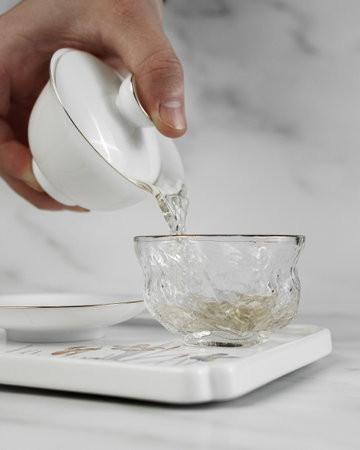 An Elegant Teapot Pouring Aromatic Tea into a Glass Cup, Celebrating Serenity and Traditionの写真素材