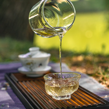 Enjoy an Elegant Tea Ceremony in Nature, with a Glass Teapot and Cups for tranquilityの写真素材
