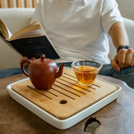 Enjoy a soothing and relaxing tea time experience with a delightful book and elegant teapotの写真素材