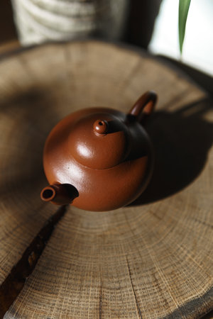 An Elegant Brown Teapot is beautifully displayed on a Wooden Surface, illuminated by Natural Lightの写真素材