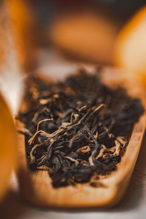 Dried Black Tea Leaves Carefully Placed in a Wooden Spoon Awaiting Preparation and Brewingの写真素材