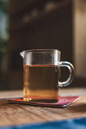 An Elegant Glass Teapot Resting on a Wooden Surface in a Cozy and Inviting Settingの写真素材