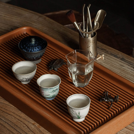 A Traditional Tea Set accompanied by Utensils beautifully arranged on a Wooden Tray