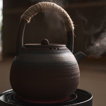 An Elegant Black Teapot with Steam Floating Above it on a Calm and Quiet Morningの写真素材
