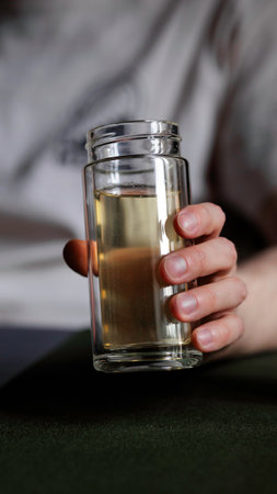 A hand holds a glass of liquid, showcasing its refreshing qualities for socializingの写真素材