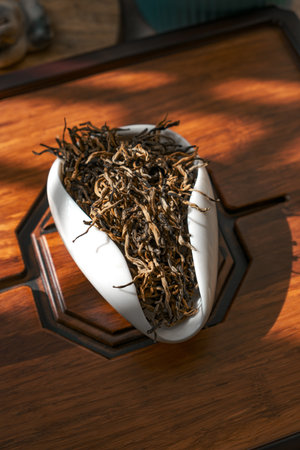 An Elegant Tea Leaf Display Presented in a Unique Bowl Set on a Beautiful Wooden Surfaceの写真素材