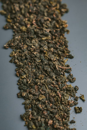 Dried Green Tea Leaves resting elegantly on a Shaded Gray Background, showcasing their beautyの写真素材