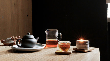 A Serene and Inviting Tea Time Setup Complete with Pot, Cup, and Flickering Candle Lightの写真素材