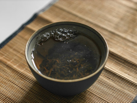 Enjoying the delightful experience of steaming tea served in a traditional bowl atop a bamboo matの写真素材