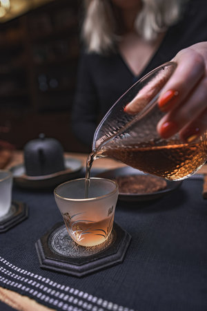 Pouring a cup of exquisite tea in a warm and cozy setting, accompanied by elegant glassware