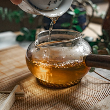 Tea is poured into a beautiful glass teapot, releasing delicate steam that dances aboveの写真素材
