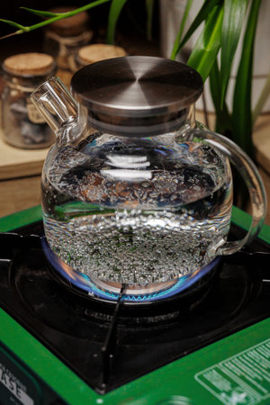 Boiling Water in a Clear Glass Kettle Placed on a Beautiful Green Stove for Tea Preparation