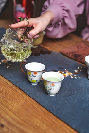 An Elegant and Beautiful Tea Pouring Ceremony Featuring Delicate Cups and Fresh Green Tea