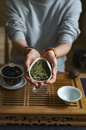 Two Hands Gently Holding Fresh, Vibrant Green Tea Leaves in a Serene Tea Ceremony Setting