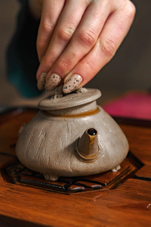 Carefully Hand Placing the Lid on a Traditional Teapot During a Serene Tea Ceremonyの写真素材