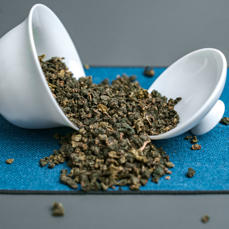 Oolong Tea Leaves are elegantly placed in white cups on a vibrant blue backgroundの写真素材