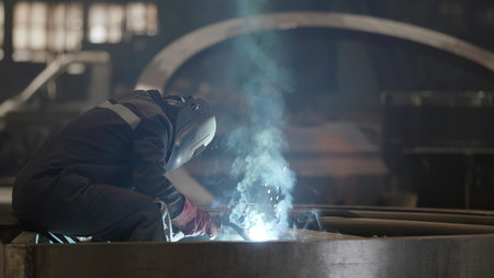 A skilled welder diligently working in an industrial workshop, actively engaged in their craft....