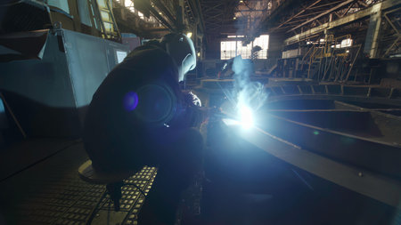 A Welder Engaged in Their Craft in an Industrial Setting with a Bright Welding Arc Visible. Stock...