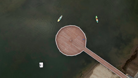 Aerial View of Stunning Circular Pier Surrounded by Boats Floating in Calm, Serene Water. Clipの写真素材