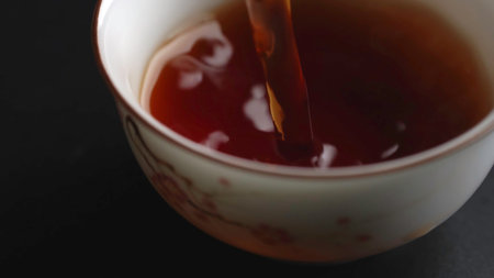 Gently Pouring Tea into a Beautifully Crafted Delicate Cup with a Creamy Swirl Design. Mediaの写真素材