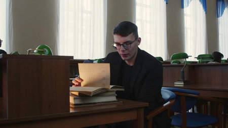 A dedicated student is completely engaged in their study while seated at the library desk. Media