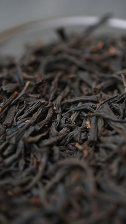 A close up view of beautifully dried black tea leaves displayed neatly in an elegant bowl. Media