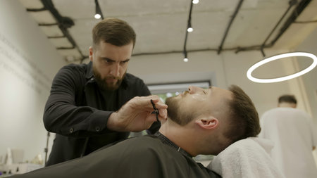 Professional barber shaving a clients beard with a straight razor. Clip