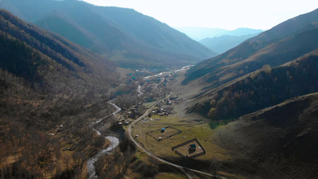 Mountain valley with winding river and small village.の写真素材