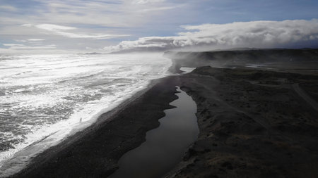 Fog rolling over black sand beach and river estuary