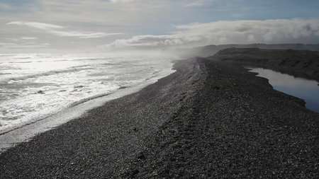 Ocean waves crashing on black sand beachの写真素材