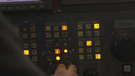 Engineer operating industrial control panel with illuminated buttons. Stock clip