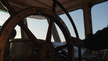 Captain steering ship through calm waters at sunrise. Clipの写真素材