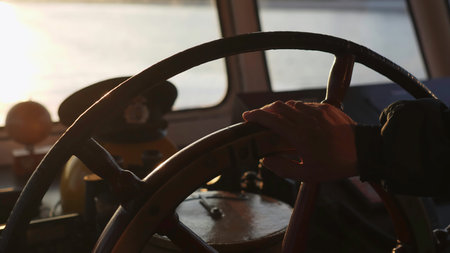 Captain steering ship wheel on bridge during golden hour. Clip